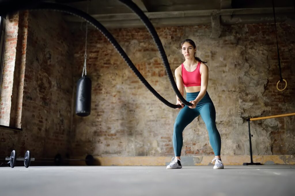 HIIT WORKOUTS - 3 DIFFERENT WORKOUTS GUARANTEED TO GET THE BLOOD PUMPING 3 Young woman exercising with battle ropes at the gym. Strong female athlete doing crossfit workout
